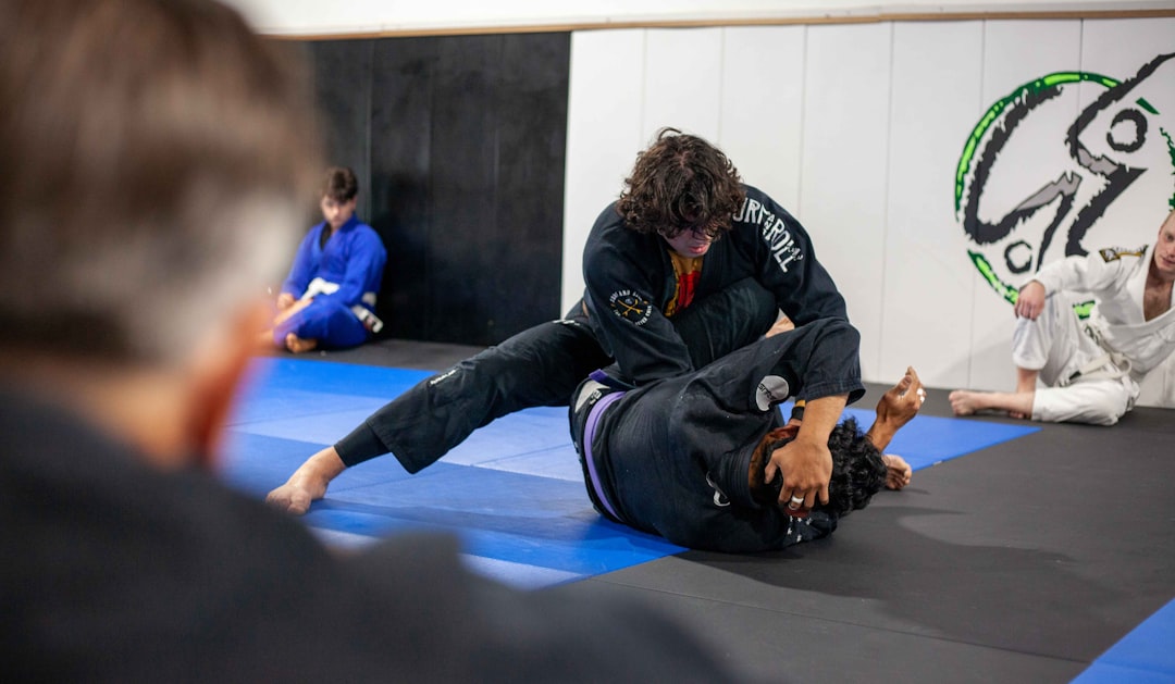 Two people practice jiu-jitsu in a gym wearing BJJ rashguards
