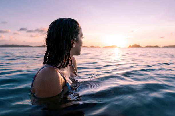 woman swimming in sea looking at sun - swim ocean sunset stock pictures, royalty-free photos & images