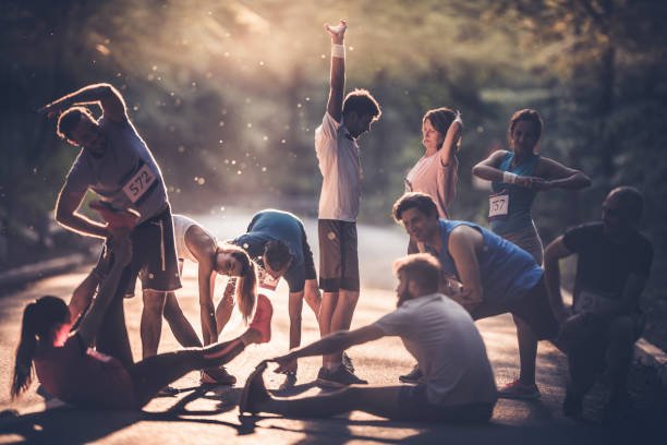 large group of runners warming up on a road at sunset before the marathon. - athlete warm up stock pictures, royalty-free pho