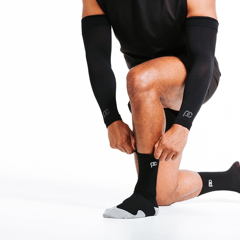Man wearing PRO Compression black arm sleeves and crew compression socks.