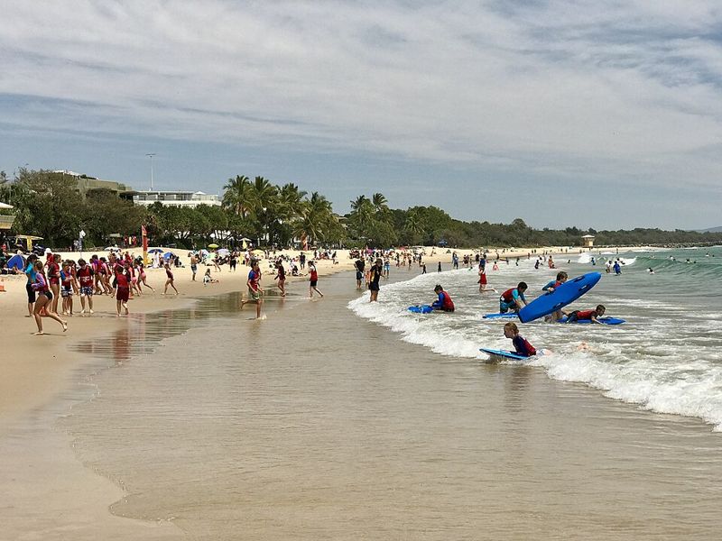 Children in rashguards learning to surf at the beach with bodyboards