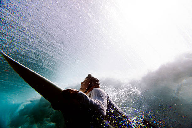 Surfer duck diving Surfer duck diving under reef break surfer-duck-dive stock pictures, royalty-free photos & images