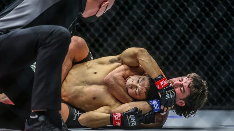 Rear naked choke submission in a no-gi MMA cage fight