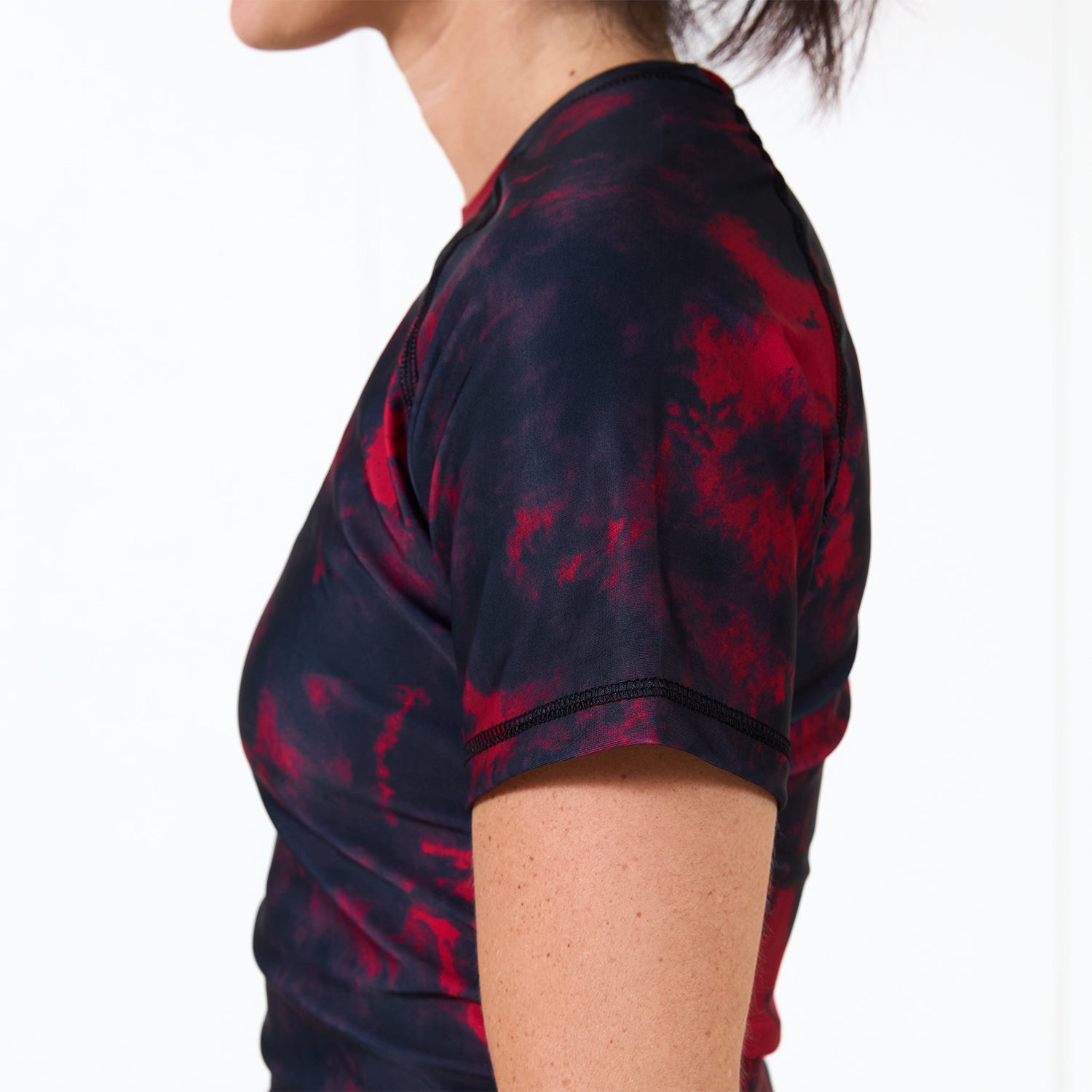 Side profile of the Womenโs Ember BJJ Rash Guard highlighting the slim athletic fit and red-black colorway.