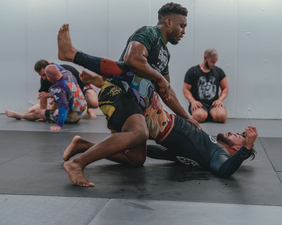 No-gi BJJ grappling training on the mat — athletes in rashguards and compression shorts
