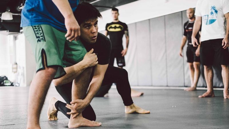 No-gi grappler in a rashguard shooting a double leg takedown