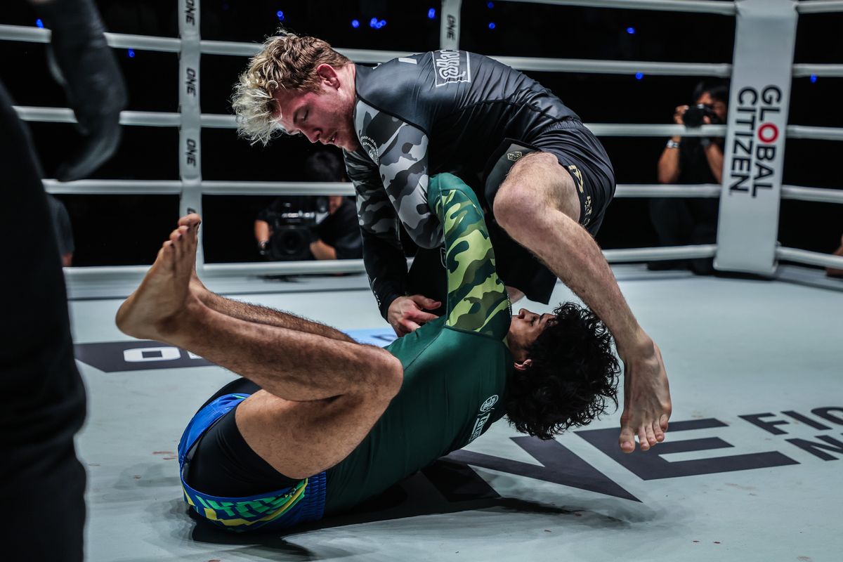 A no-gi grappler executing the knee cut pass over his opponent guard