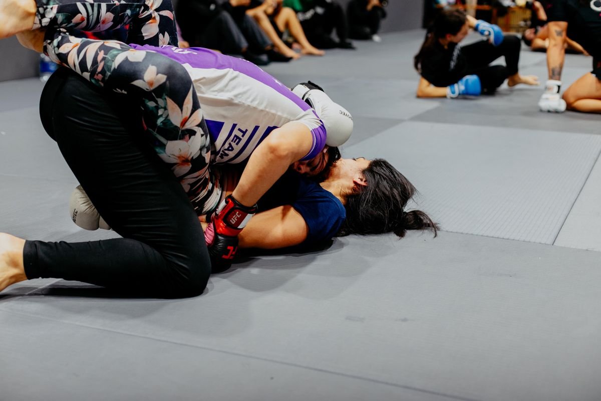 Female BJJ athletes training no-gi in rashguards on the mat