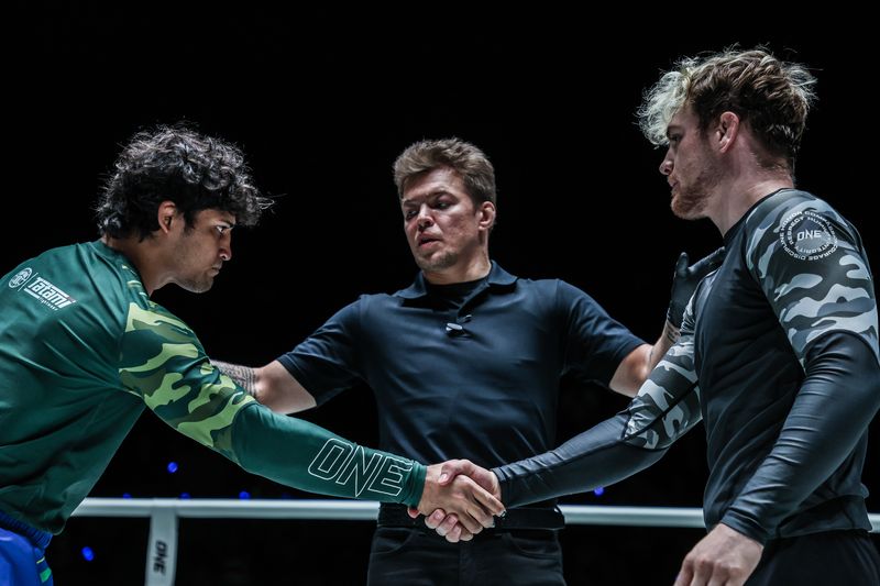 Two no-gi grapplers in rashguards shaking hands to start a match