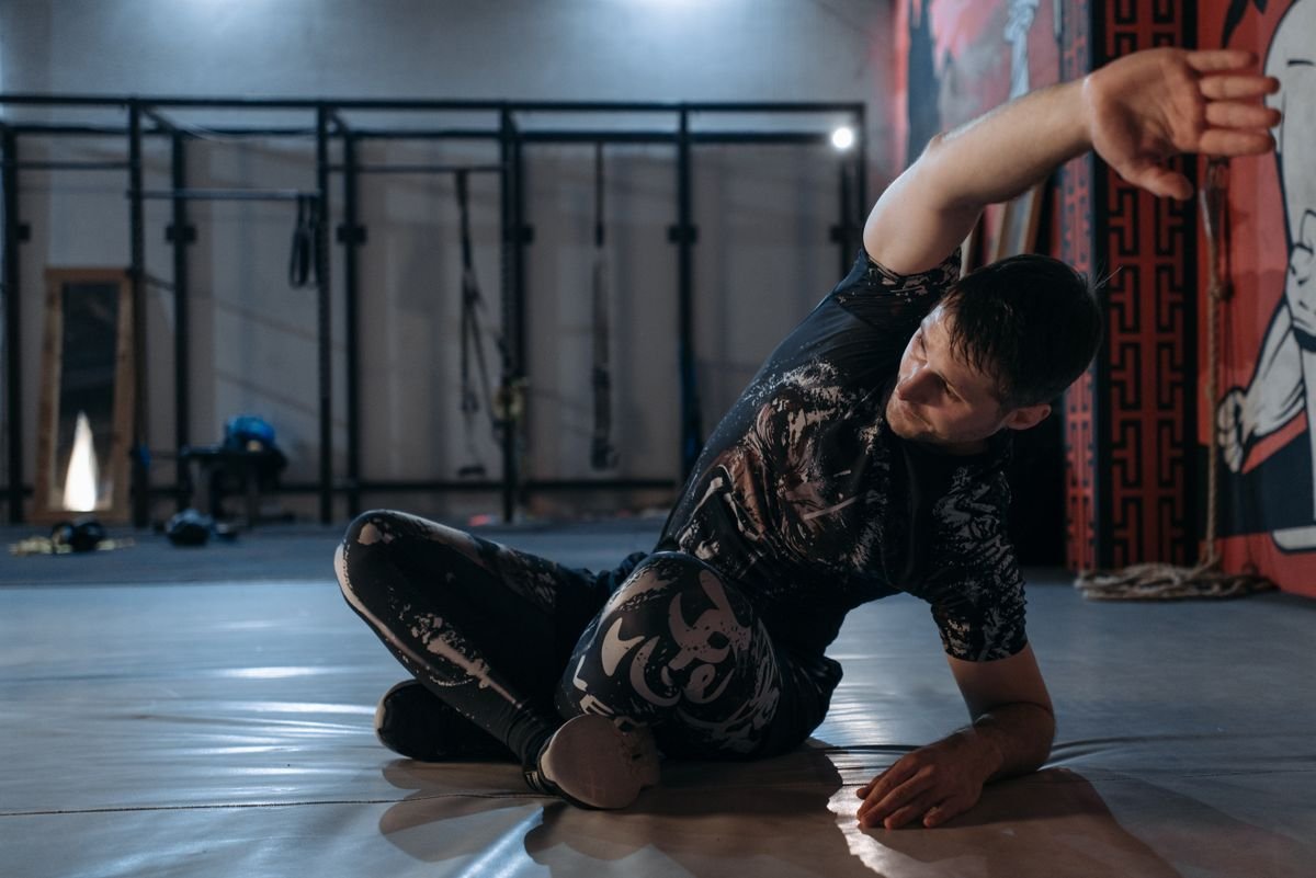 Grappler in a BJJ rashguard working a position on the training mat