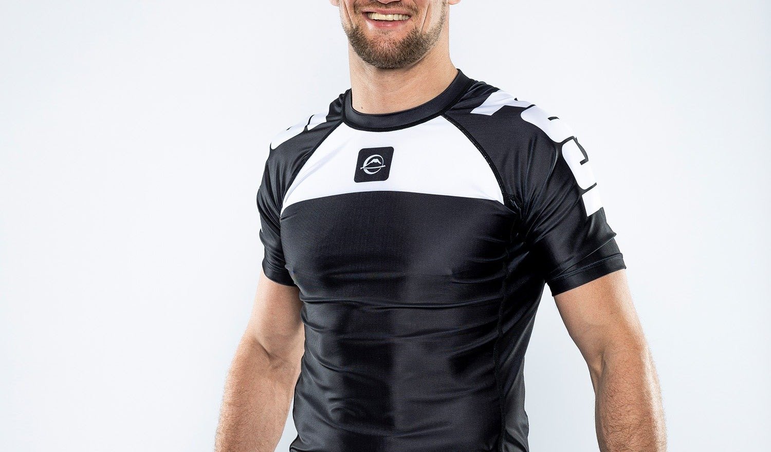 No-gi grappler wearing a black and white compression rashguard that stays flush against the chest and shoulders