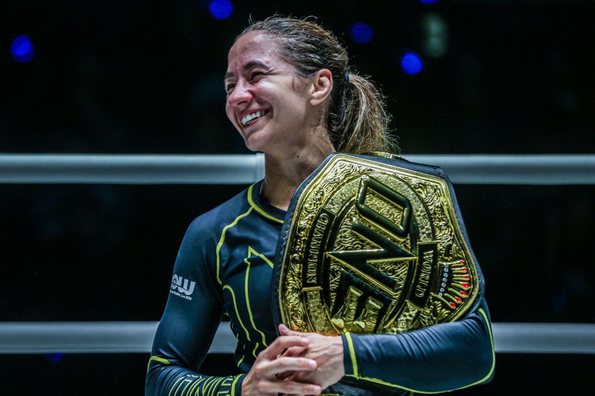Mayssa Bastos holds her championship belt after a no-gi submission grappling win