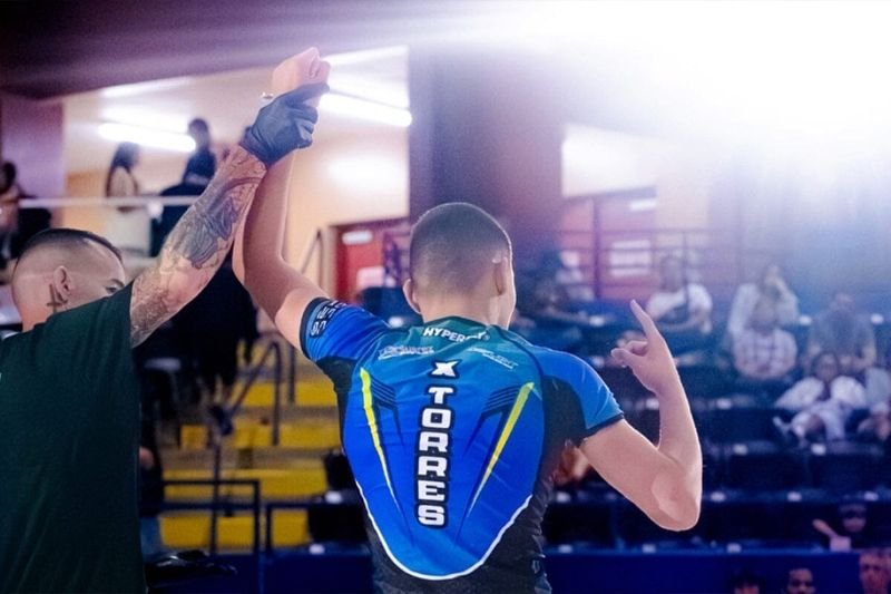 No-gi grappling competitor with hand raised after a match