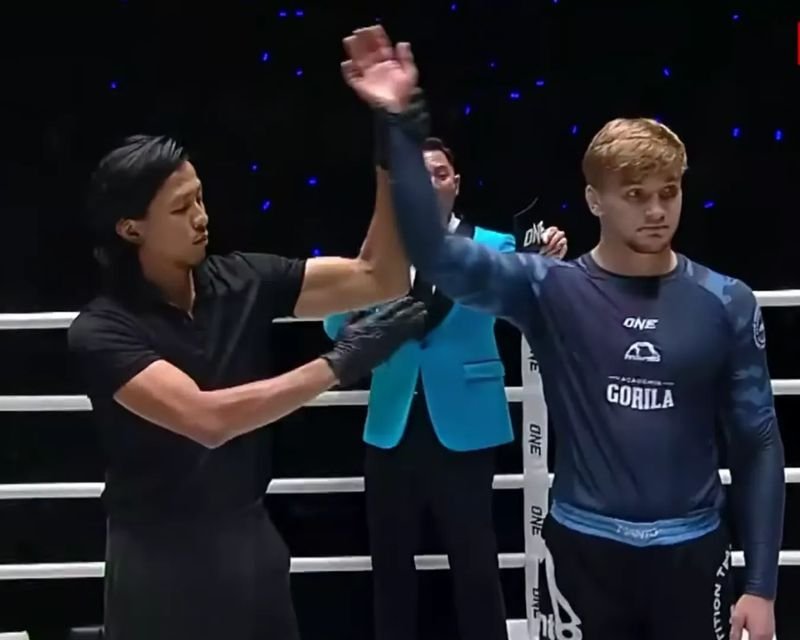 No-gi competitor with hand raised in victory wearing a compression rashguard