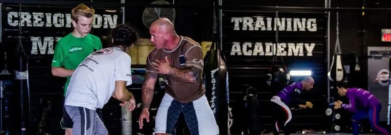 Grapplers training together at a no-gi gym, several wearing rashguards in rotation