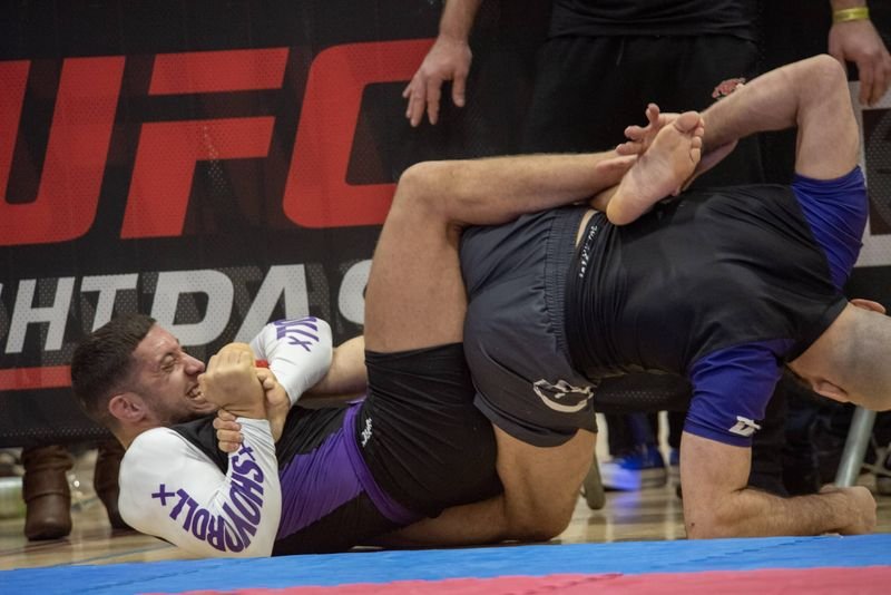 taped wrists visible during no-gi BJJ leg lock exchange at ADCC competition