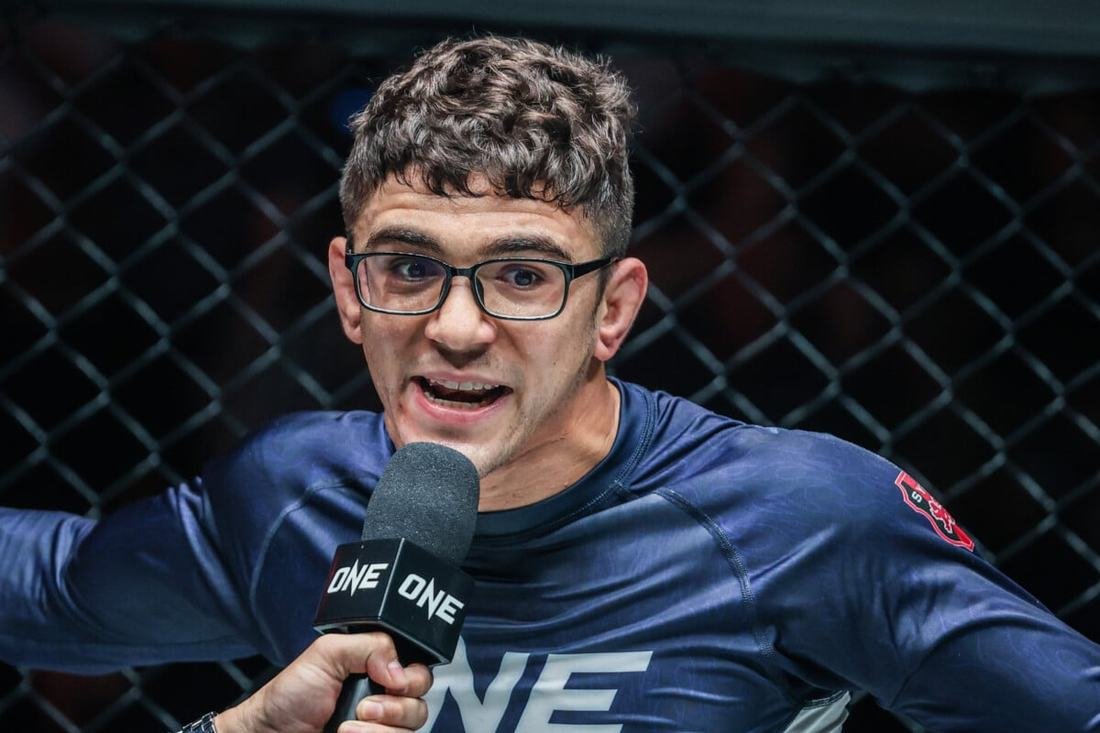 No-gi rashguard buying guide reference: a grappler's long-sleeve rashguard holding up during a post-match interview