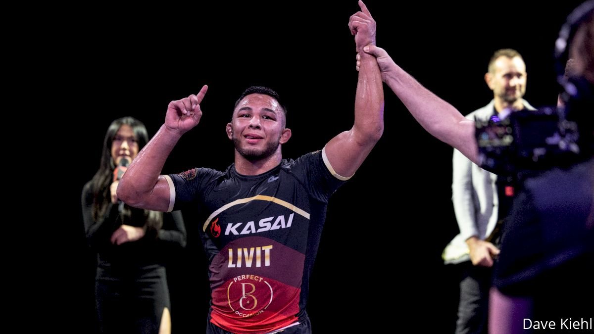 No-gi grappler in a competition rashguard celebrating a win with arms raised