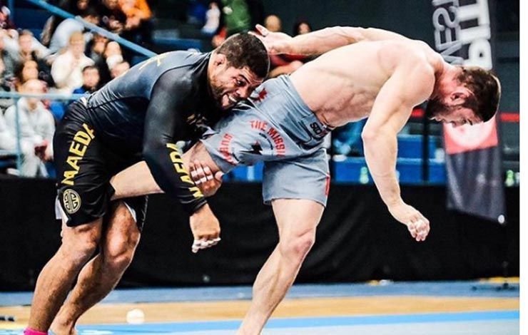 No-gi grappler finishing a double leg takedown throw in competition