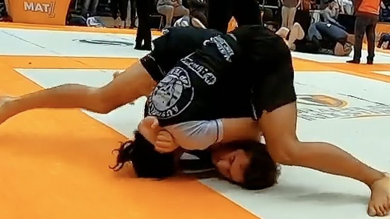 A competitor finishes a no-gi baseball choke on the mat during a jiu-jitsu tournament