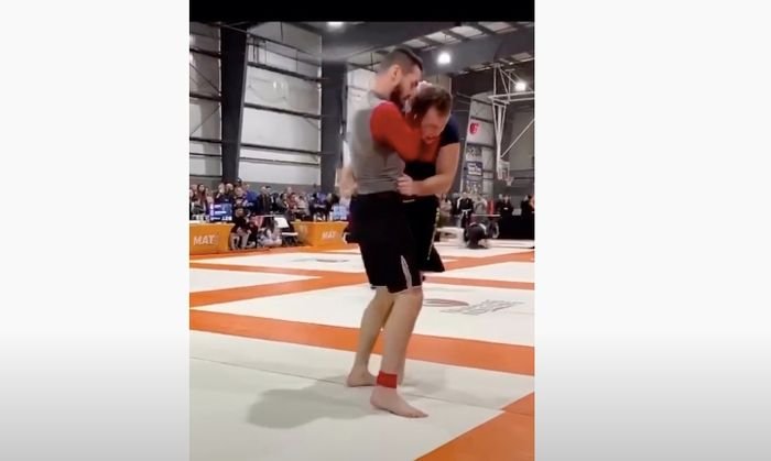 A grappler locks in a standing reverse no-gi baseball choke at a Grappling Industries event