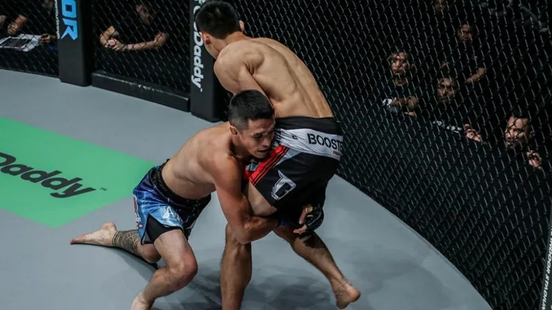 Fighter driving through a takedown attempt in the cage