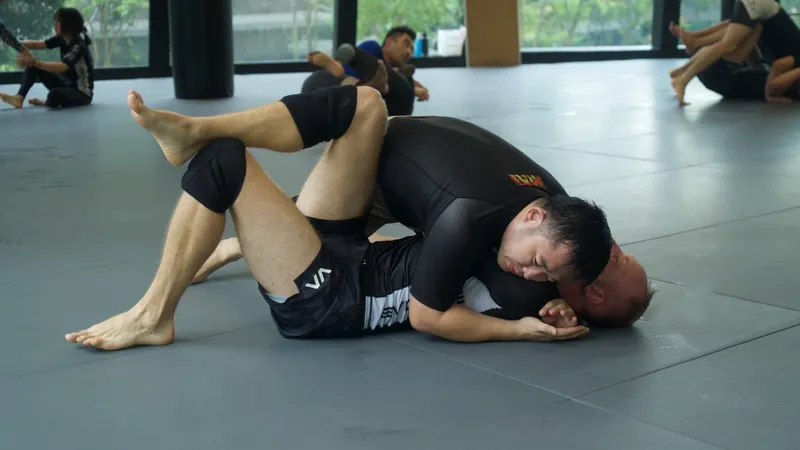 No-gi grapplers training on the mat in rashguards after a takedown