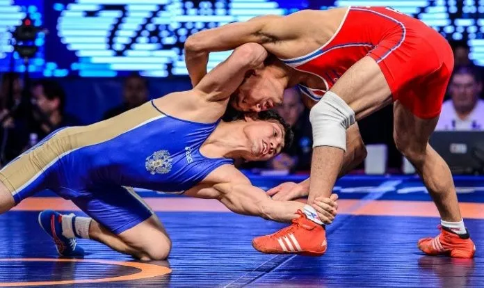 Freestyle wrestler executing an ankle pick takedown at the World Championships