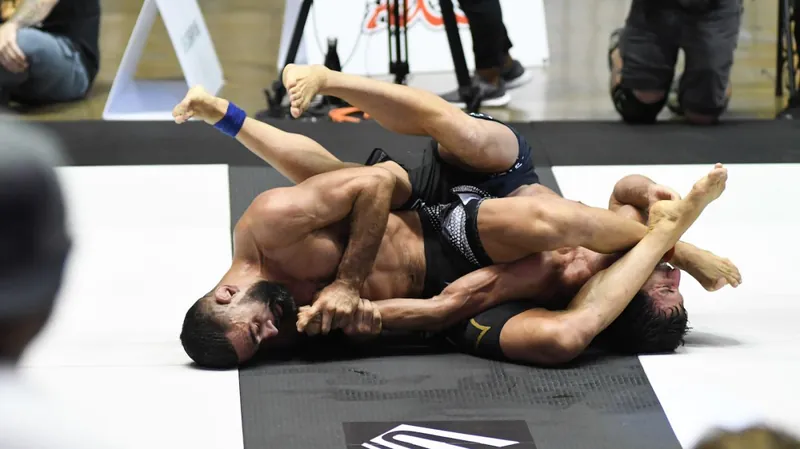 No-gi grapplers scrambling for back control during a bow and arrow choke setup